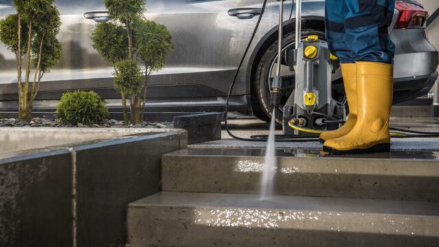 Homeowner Washing His Garden Paths and Driveway Using Pressure Washer