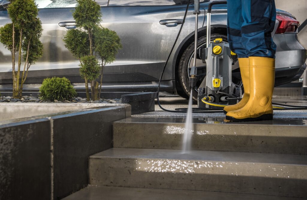 Homeowner Washing His Garden Paths and Driveway Using Pressure Washer